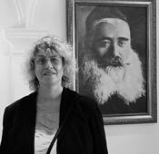 Анна Медалье, правнучка Витебского раввина Шмер-Лейба Медалье, рядом с портретом прадеда на открытии Большой Любавичской синагоги в Витебске, июль 2023 г.