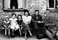 На снимке: родители и я, а рядом со мной – мои двоюродные сестры Марина и Света Мовзон. Мы сидим себе на нашей лавочке на солнышке под нашим окном. Мне три года. Платье – темно-синего шелка в цветочек. Я его помню, бабушка сшила.